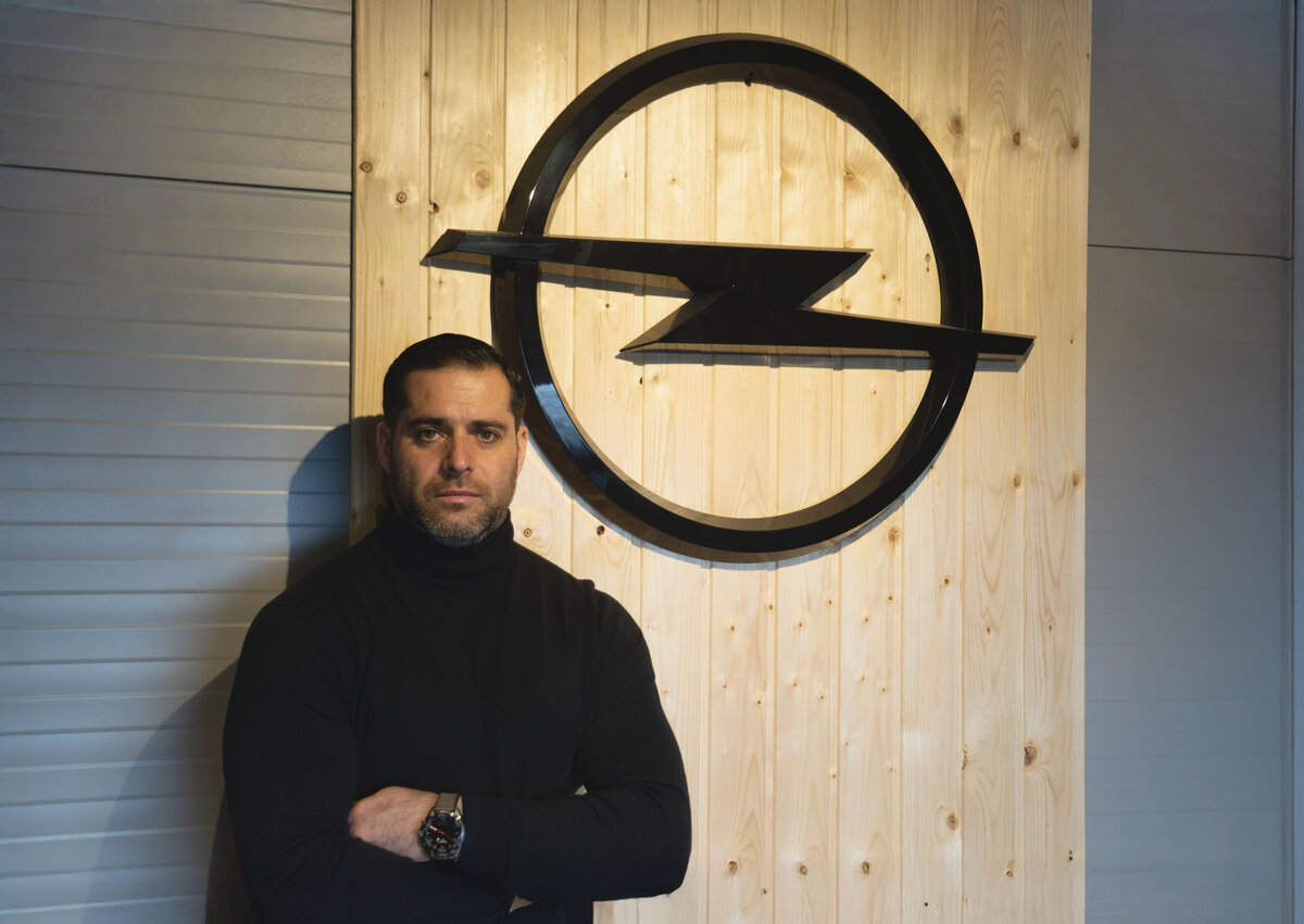 Adam Gile - portret cu logo Opel pe perete, fondator Service Adam Cluj